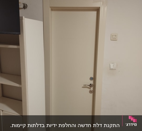 דלת לבנה עם ידית מתכת ליד ארון קיר